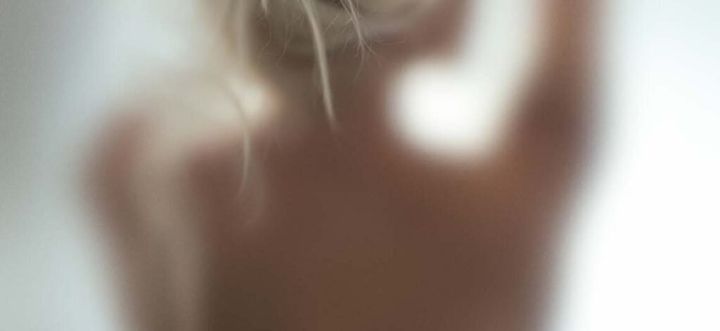 Woman taking a shower behind glass